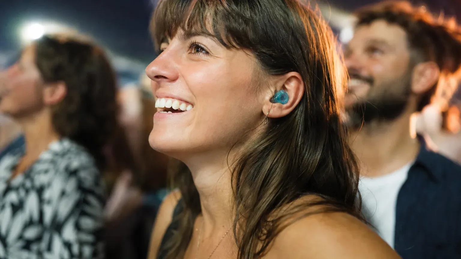 Personne portant des bouchons d'oreilles lors d'un concert avec des lumières colorées