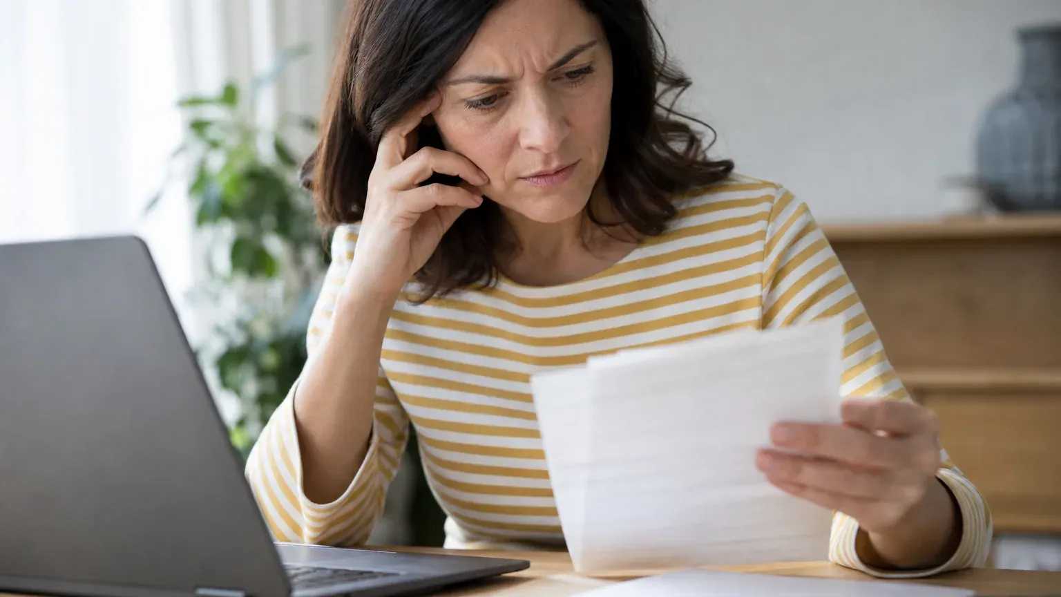 Personne vérifiant un relevé bancaire pour repérer un prélèvement non autorisé