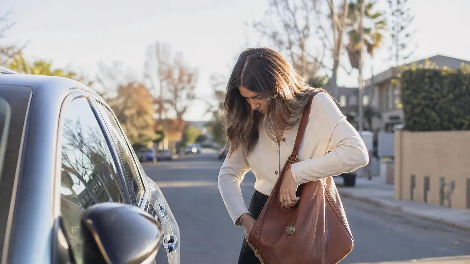 Personne fouillant son sac à la recherche de ses clés à côté d'une voiture garée
