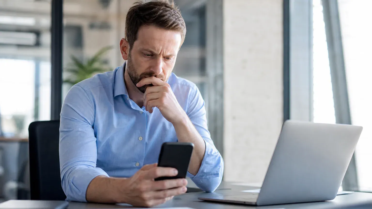 Personne consultant son relevé de compte bancaire sur son smartphone à son bureau