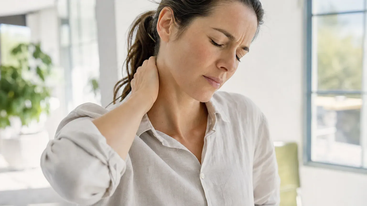 Personne debout se tenant la nuque, la tête inclinée par la douleur d'un torticolis